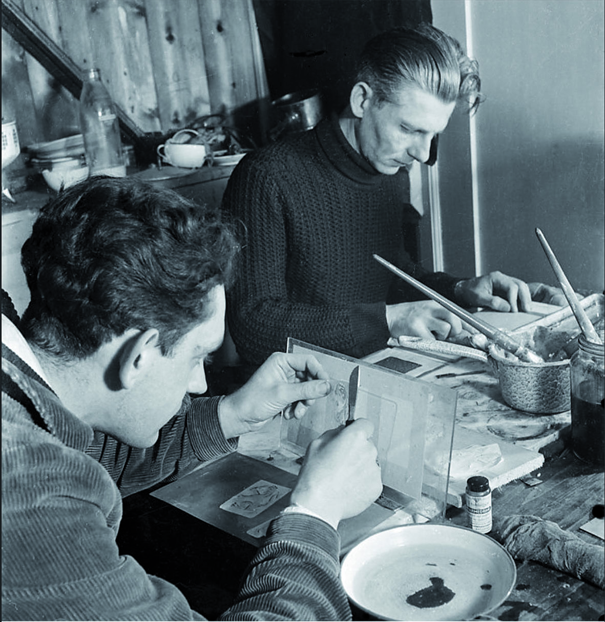 Leden van de ondergrondse Persoonsbewijzen Centrale (PBC) maken tijdens de Tweede Wereldoorlog vervalste identiteits­papieren voor onderduikers en het verzet, Amsterdam. Rechts: Walter Brandligt. (Bron: Nederlands Fotomuseum, foto: Violette Cornelius)